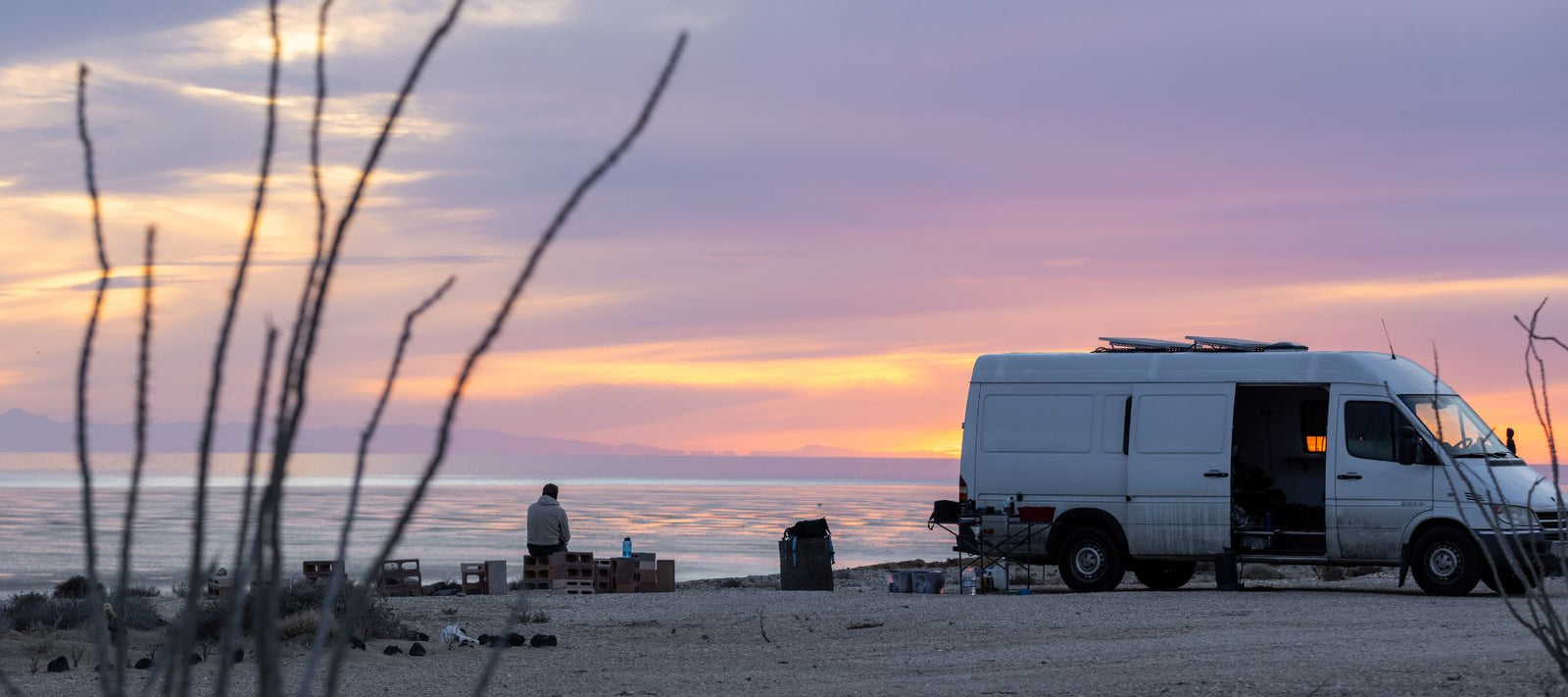van parked by ocean with beautiful sunset behind
