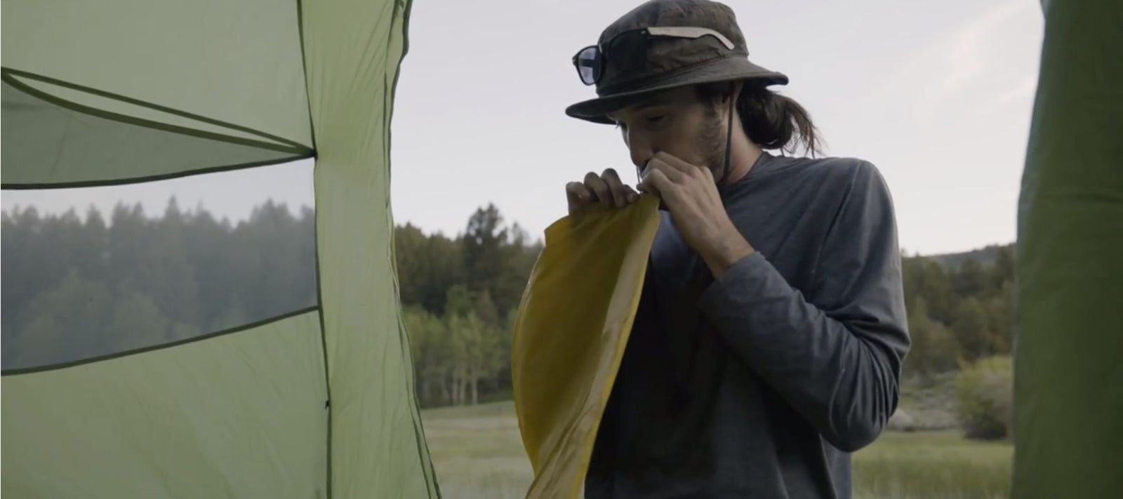 man blowing up sleeping pad to go camping