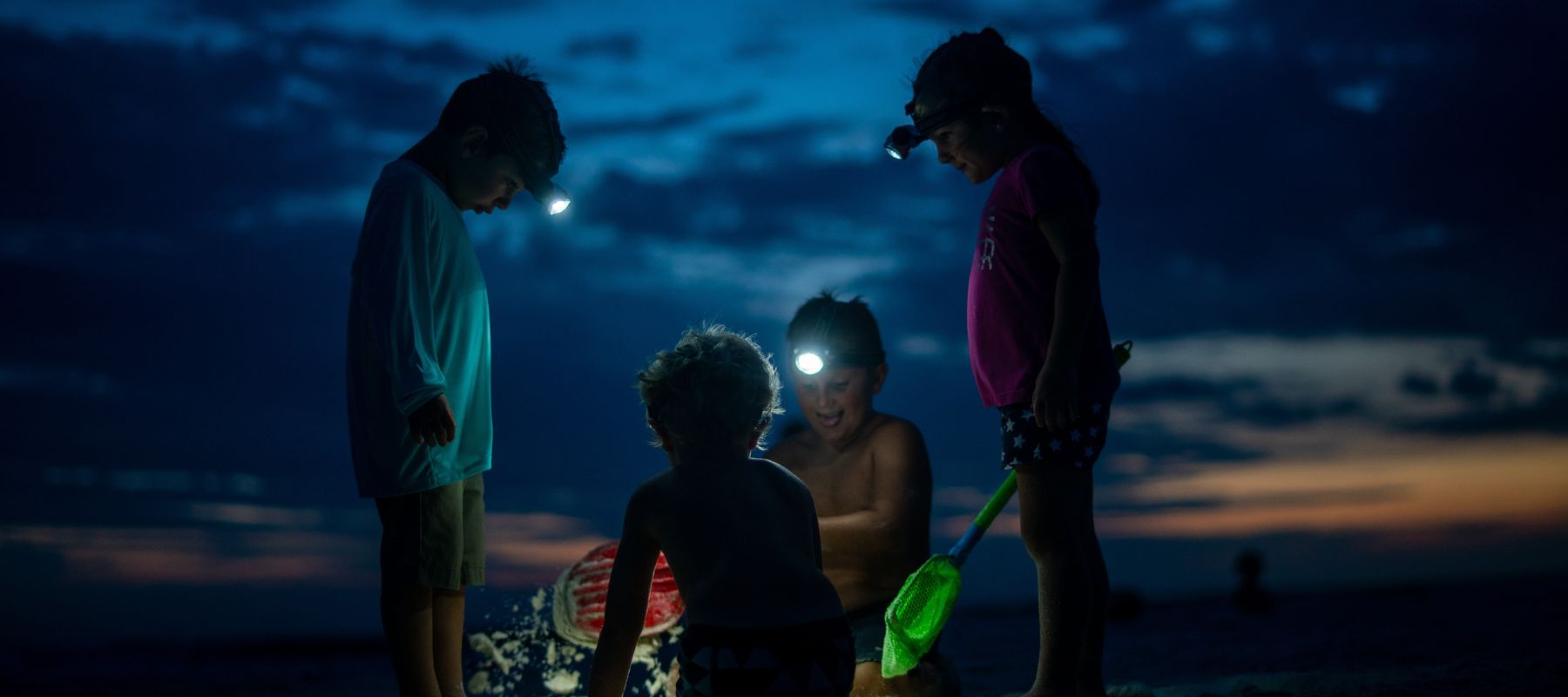kids wearing headlamps camping on the beach