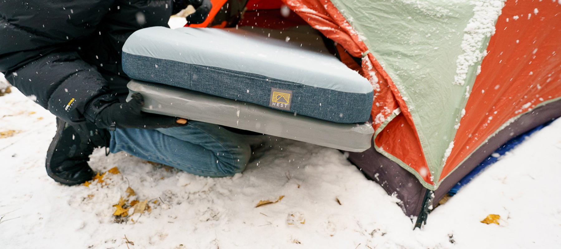 HEST sleep system used in a snowy landscape being placed inside a tent during winter.